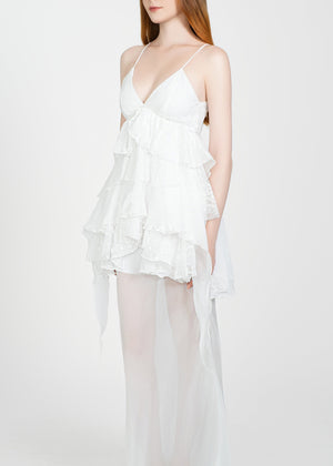 Woman wearing a white dress with sheer overlay on a white background