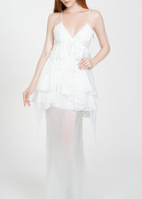 Woman wearing a white dress with sheer overlay on a white background