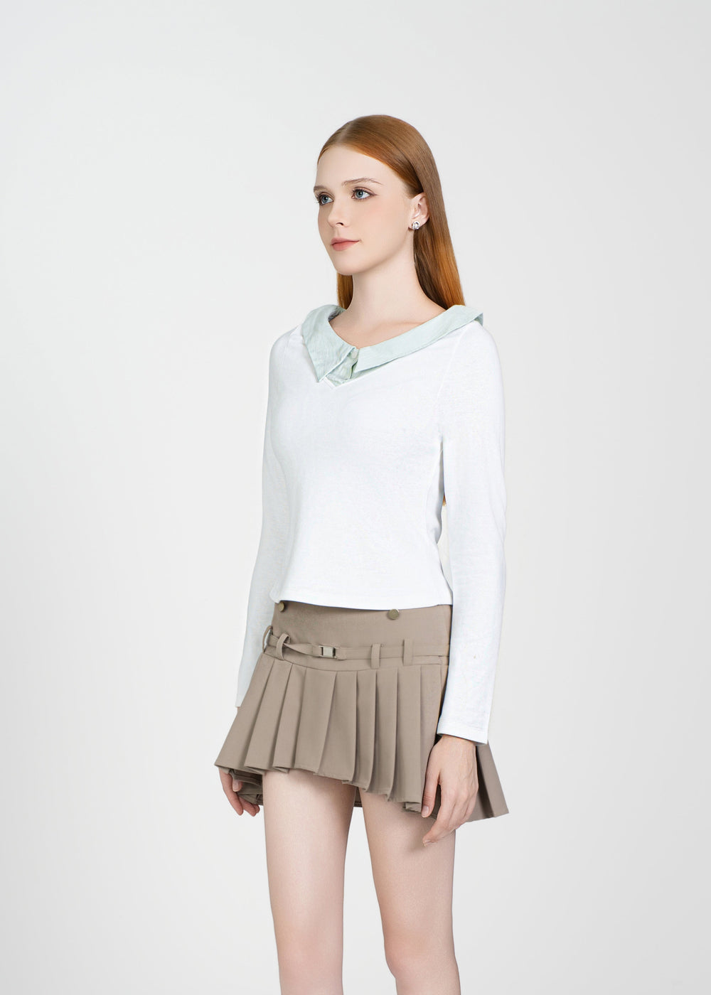 Woman wearing a white long-sleeve top and beige pleated skirt on a white background
